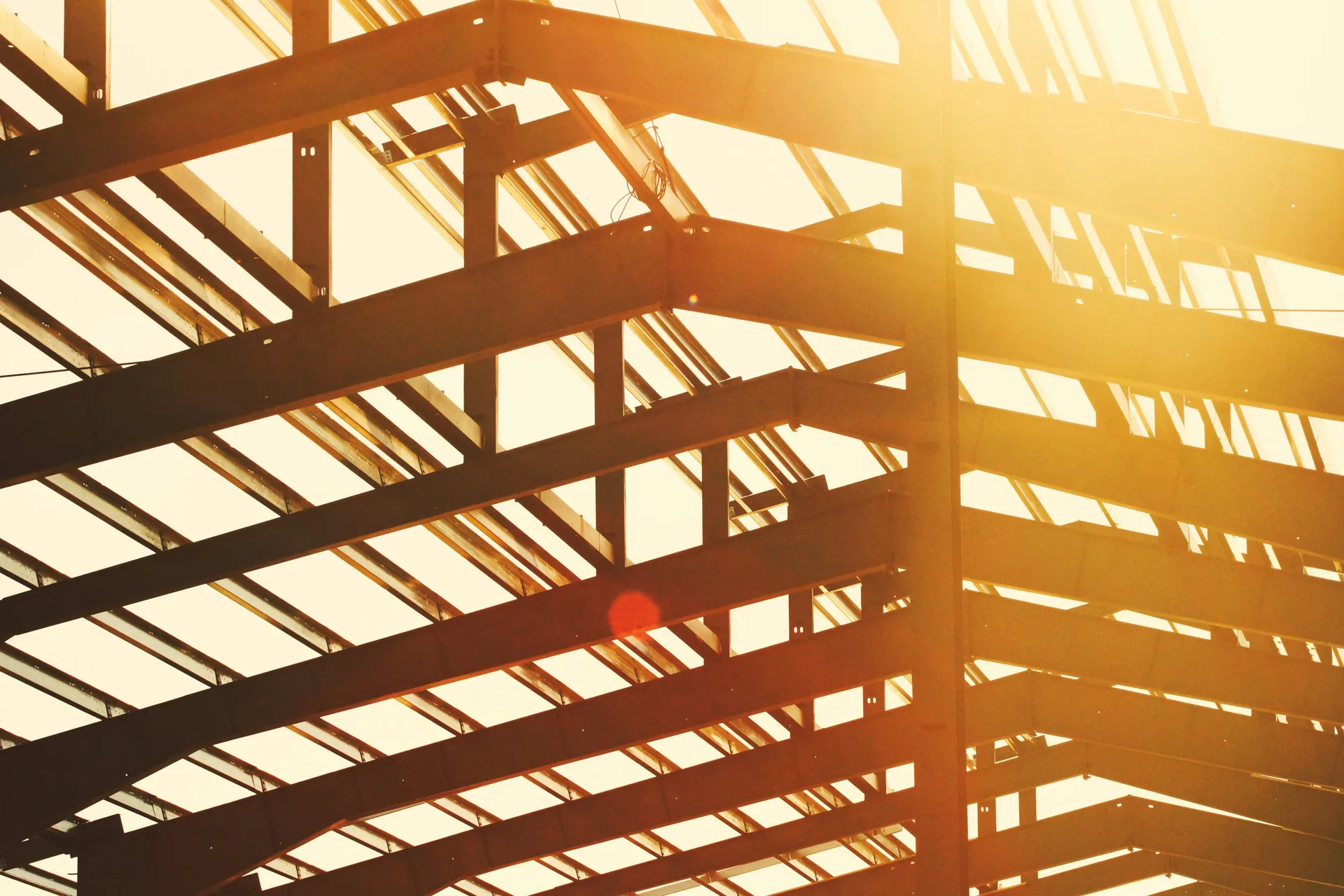 Steel structural frame of a building backlit by golden sunset light