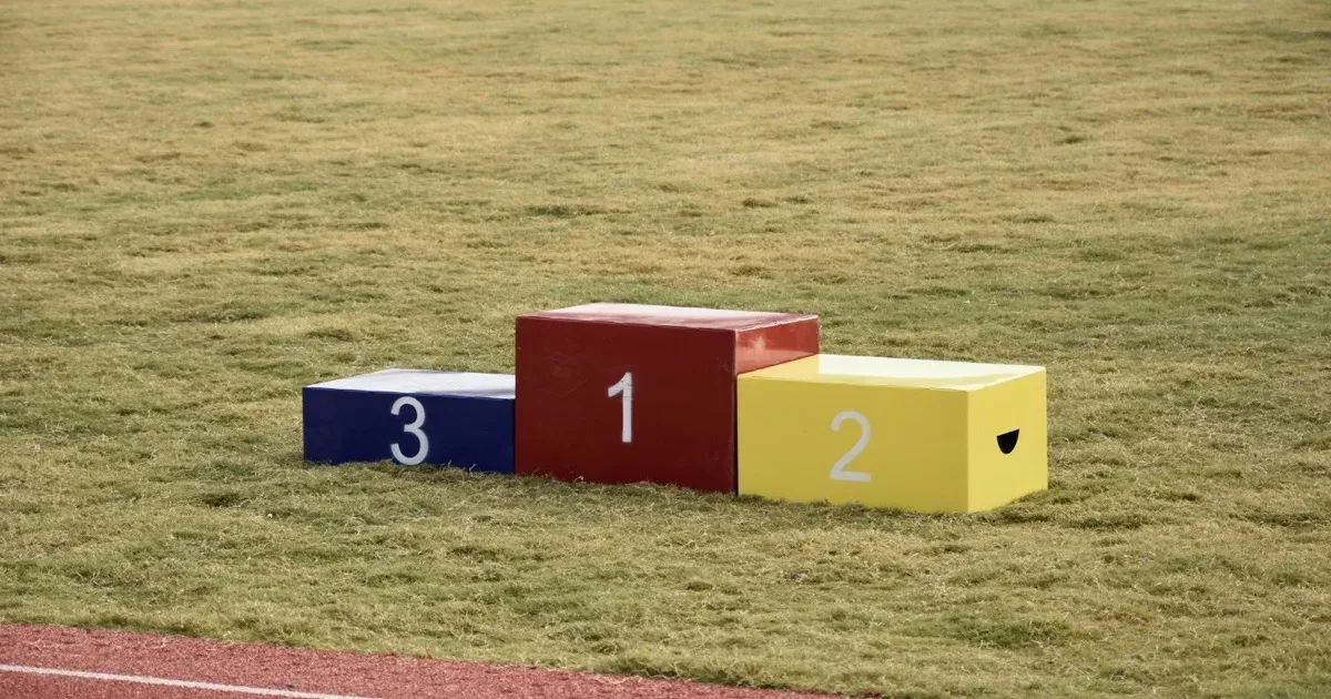 An empty winners' podium numbered one, two, and three on a sports field
