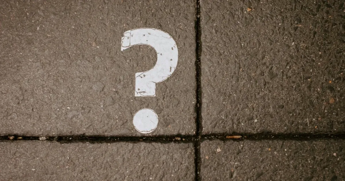 A white question mark painted on a concrete pavement